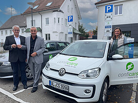 Zwei Fahrzeuge stehen für Carsharing-Kunden in Günzburg auf dem Degele-Parkplatz bereit: Conficars-Geschäftsführer Joachim Vogt (links) übergibt Oberbürgermeister Gerhard Jauernig die Autoschlüssel, Klimaschutzmanagerin Daniela Fischer ist bereit für die erste Fahrt. Foto: Michael Lindner/Stadt Günzburg