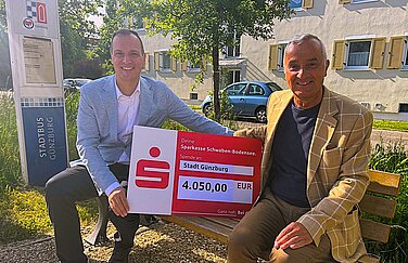 Am Mittleren Stadtbach lässt sich ab sofort bequem im Sitzen auf den Bus warten. Daniel Gastl (links) ermöglichte mit einer Spende der Sparkasse Schwaben-Bodensee die Anschaffung zur Freude von OB Gerhard Jauernig.  Foto: Monika Rudolph/ Stadt Günzburg