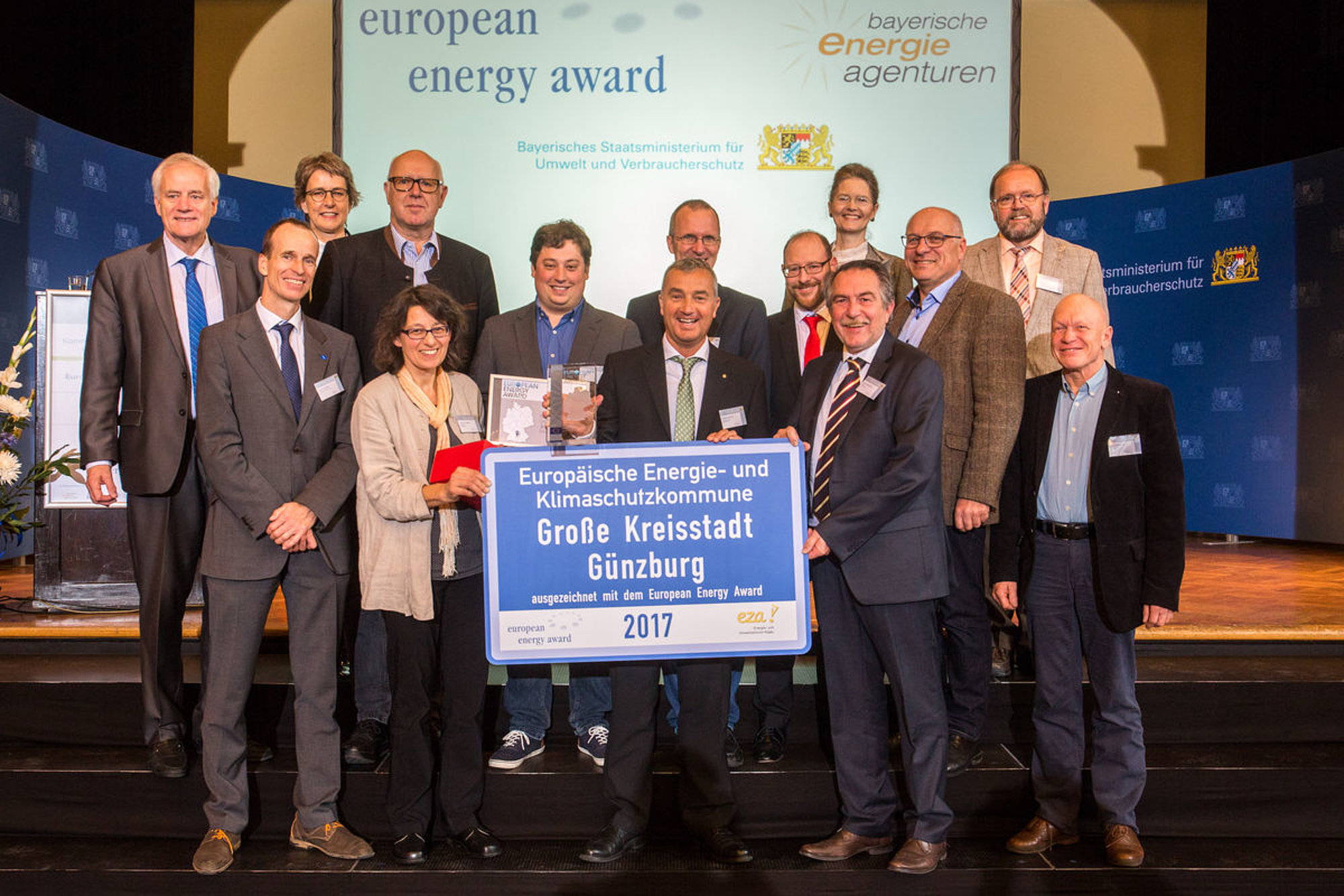 Die strahlenden Gesichter vom Energieteam der Stadt Günzburg mit Gratulanten bei der eea-Preisverleihung in München: Walter Steinmann (Vorstandvorsitzender Europäischer Verein European Energy Award), Martin Sambale (eza!-Geschäftsführer), Ilga Schwidder (Geschäftsführerin Bundesgeschäftsstelle European Energy Award), Hubert Steber, Christine Hengeler, Roman Holl, Oberbürgermeister Gerhard Jauernig, Dr. Hans-Jörg Barth (eea-Berater von eza!), Jörg Stein, Johann Kaltenecker, Dr. Monika Kratzer (Ministerialdirigentin im bayerischen Staatsministerium für Umwelt und Verbraucherschutz), Josef Nersinger, Johann Stelzle, Hartmuth Hoeber. Foto: Bayerisches Staatsministerium für Umwelt und Verbraucherschutz.