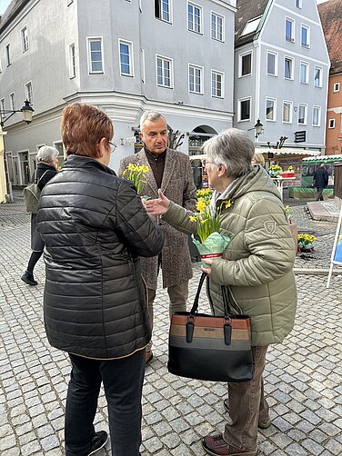Günzburgs Oberbürgermeister Gerhard Jauernig verteilte auf dem Marktplatz Osterglocken und sprach mit den Menschen über die Landesgartenschau 2029. Foto: Julia Ehrlich/ Stadt Günzburg