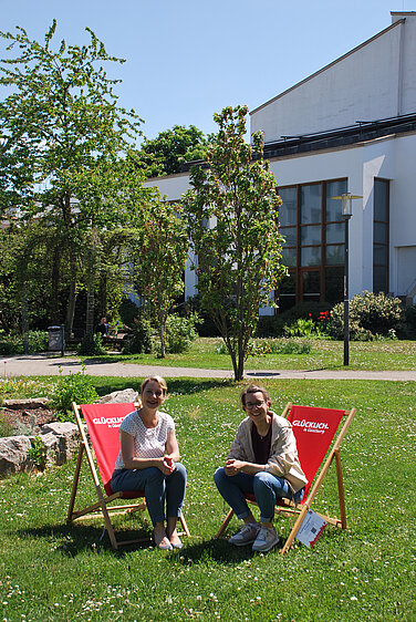 Kulturamtsleiterin Karin Scheuermann (links) und Citymanagerin Nikola Gamm testen die „Glücklich“-Liegestühle im Günzburger Hofgarten. Foto: Johanna Hofgärtner/Stadt Günzburg