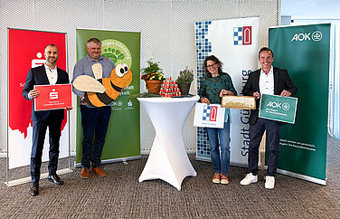 Die Bienenpaten Andreas Steinbacher, Christine Hengeler und Bernd Mayer heißen die Bienen von Imker Wolfgang Heininger in der Stadt Günzburg willkommen. Die Bienenpaten Andreas Steinbacher, Mitglied des Vorstands der Sparkasse Schwaben-Bodensee, Christine Hengeler, Umweltfachkraft der Stadt Günzburg, und Bernd Mayer, Direktor der AOK Günzburg, heißen die Bienen von Imker Wolfgang Heininger, Vorsitzender des Imker-Kreisverbandes Günzburg, symbolisch mit einer großen Holzbiene für die Blühflächen in der Stadt Günzburg herzlich willkommen. Foto: Demet Karatas/Sparkasse Schwaben-Bodensee
