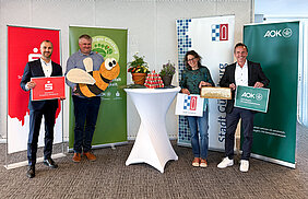Die Bienenpaten Andreas Steinbacher, Mitglied des Vorstands der Sparkasse Schwaben-Bodensee, Christine Hengeler, Umweltfachkraft der Stadt Günzburg, und Bernd Mayer, Direktor der AOK Günzburg, heißen die Bienen von Imker Wolfgang Heininger, Vorsitzender des Imker-Kreisverbandes Günzburg, symbolisch mit einer großen Holzbiene für die Blühflächen in der Stadt Günzburg herzlich willkommen.  Foto: Demet Karatas/Sparkasse Schwaben-Bodensee