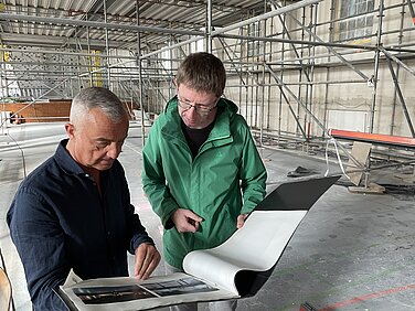 Christian Geipel vom Stadtbauamt (rechts) führt Günzburgs Oberbürgermeister Gerhard Jauernig durch die Baustelle und zeigt dabei die Sanierungspläne der Jahnhalle. Foto: Michael Lindner/Stadt Günzburg